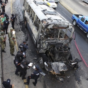 Policiais observam local onde um motorista de ônibus foi assassinado e o veículo queimado por bandidos em Acapulco, cidade turística do México - Reuters