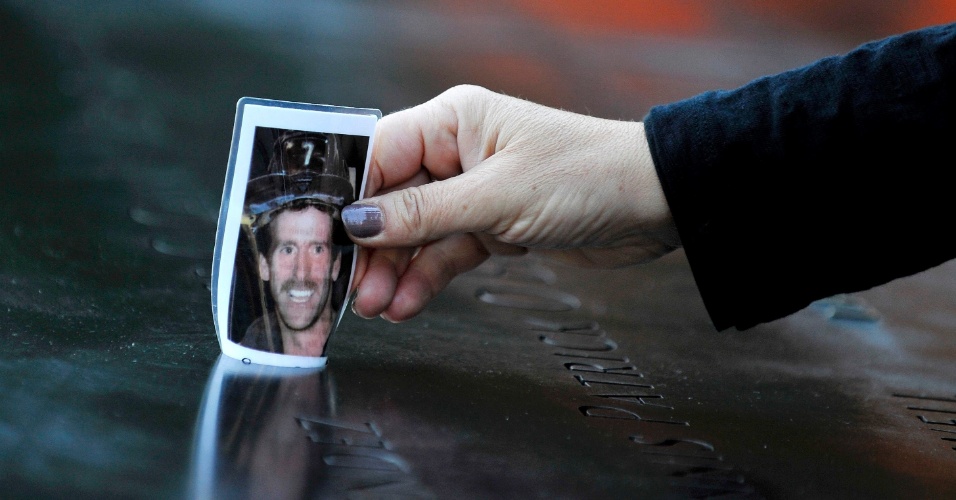 11.set.2012 - Christine Gonda coloca uma foto do bombeiro George Kane sobre monumento em homenagem às vítimas dos atentados terroristas de 11 de setembro de 2001, no World Trade Center. Kane morre nos ataques 