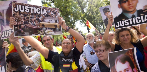 Membros da associação "Vozes contra o terrorismo" seguram fotos de vítimas do grupo ETA durante uma manifestação em Madrid contra o estatuto especial dada pelas autoridades espanholas para Iosu Uribetxeberria Bolinaga, membro preso do grupo separatista basco - Pierre/AFP