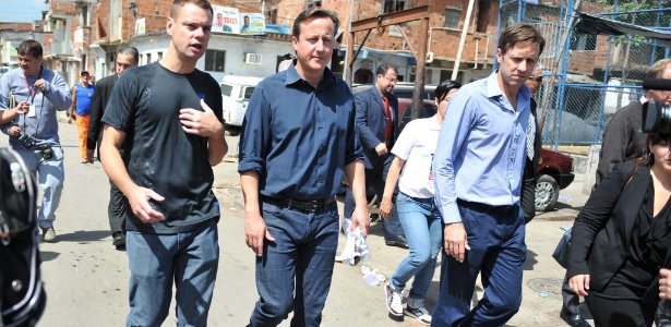 O primeiro-ministro britânico, David Cameron (centro), caminha por rua do Complexo da Maré, no Rio de Janeiro. Cameron está em visita oficial ao Brasil para se reunir com a presidente Dilma Rousseff - Vanderlei Almeida/AFP