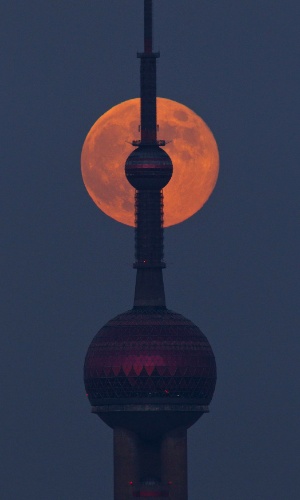 30.set.2012 - A Lua se levanta sobre o horizonte de uma torre de televisão, em Xangai, na China