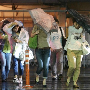 Pedestres lutam contra ventos fortes provocados pelo tufão Jelawat que atinge ilhas do Japão - Jiji Press/AFP
