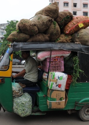 Indiano dirige auto-riquixás sobrecarregado com sacos de vegetais unidades por uma estrada em Ahmedabad, na Índia; modelos movidos a hidrogênio estão sendo implementados no país