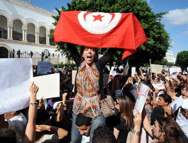 Manifestante tunisiana exibe bandeira da Tunísia durante protesto contra violência cometida contra as mulheres, em Tunis, capital do país. A manifestação ocorreu em frente a um tribunal onde uma jovem tunisiana, que teria sido estuprada por dois policiais, encara acusações de "atentado ao pudor", em um caso que espalha revolta pelo país