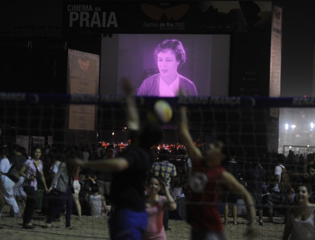 Pessoas jogam vôlei durante a exibição do filme "The Pleasure Garden", de Alfred Hitchcock, na praia de Copacabana, no Rio de Janeiro (4/10/12) - AFP PHOTO / ANTONIO SCORZA