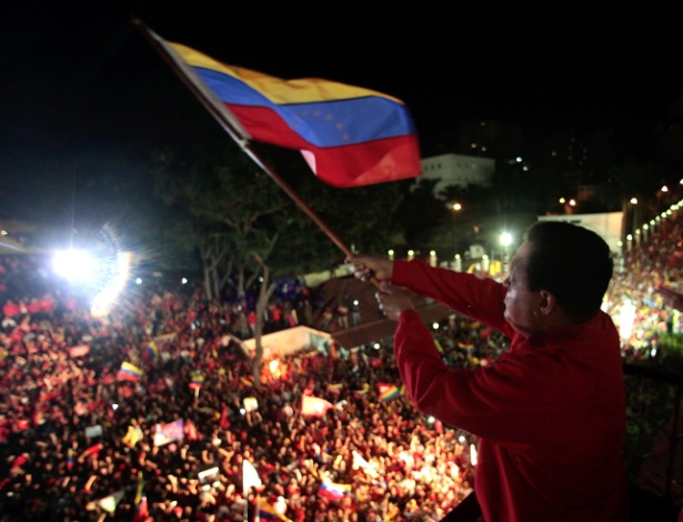 Reeleito para o cargo, o presidente Hugo Chávez balança a bandeira da Venezuela e comemora a vitória na sacada do Palácio de Miraflores, em Caracas. - Marcello Casal/ABr