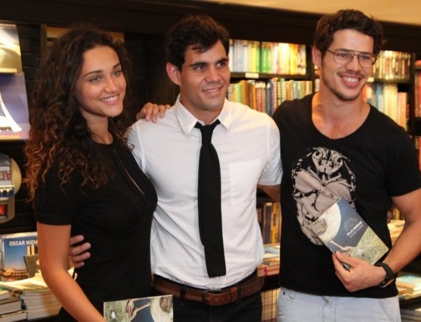 Juliano Cazarré (centro) posa para fotos com José Loreto e Débora Nascimento no lançamento do livro "Pela Janelas" na Livraria Travessa, do BarraShopping, Rio de Janeiro 