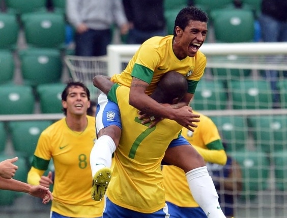 Paulinho (frente) e Ramires se abraçam em comemoração de gol da seleção brasileira