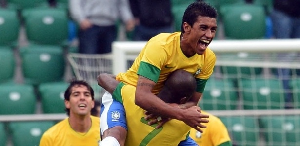Paulinho (frente) e Ramires se abraçam em comemoração de gol da seleção brasileira