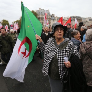 Mulher carrega bandeira nacional da Argélia na ponte de Saint-Michel, em Paris. No local, foi realizada uma passeata em memória à repressão sofrida pela Frente de Libertação Nacional (FLN) argelina há 51 anos na capital francesa