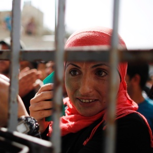 Mulher palestina aguarda para votar, no sábado (20)