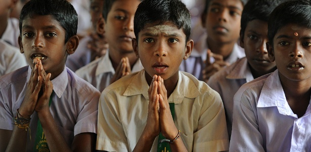 Crianças Tâmeis oram na Escola Secundária em Pudukuduirippu, no antigo bairro da zona de guerra no Sri Lanka