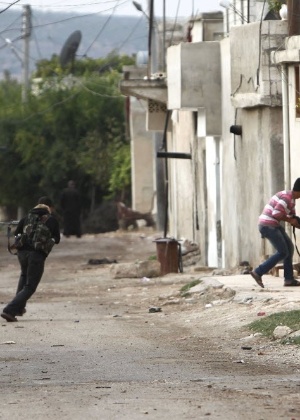 Integrante do Exército Livre Sírio se protege de disparos de atiradores do regime na cidade de Salqin, na área de Idlib
