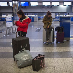 Sul-coreanas usam celular em saguão vazio do aeroporto de LaGuardia, em Nova York (EUA) - Adrees Latif/Reuters