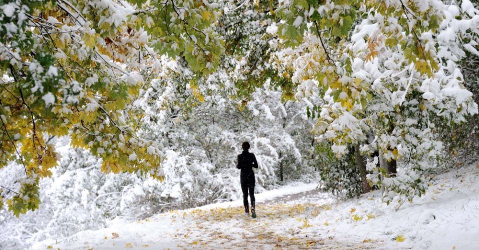 Mulher corre na neve no Parque Olímpico de Munique, na Alemanha, neste domingo (28). No primeiro dia de neve após o término do verão, nevou no sul e no leste do país