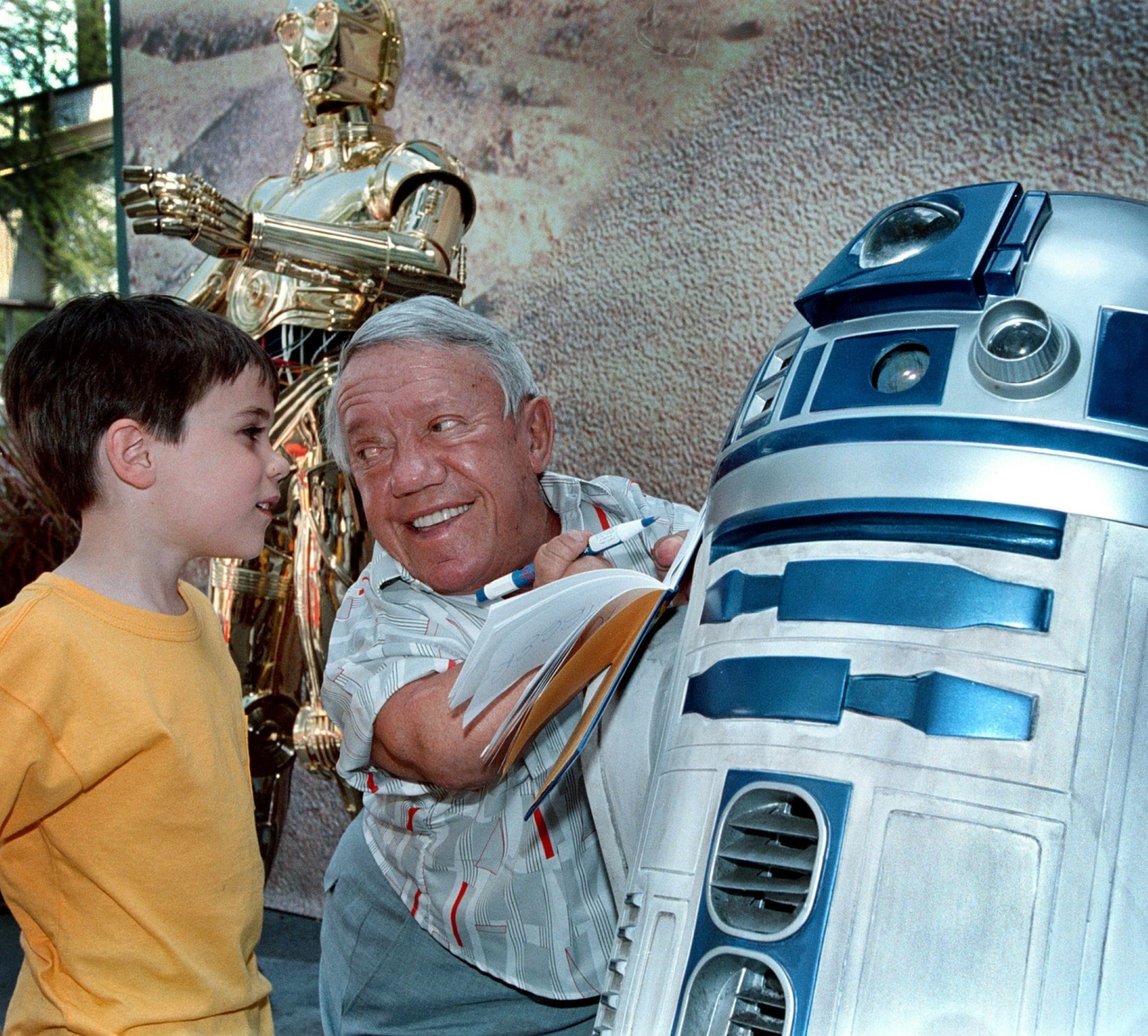 O ator Kenny Baker, que interpretou o robô R2-D2 no filme "Guerra nas Estrelas", assina autógrafo para fã na abertura do Star Wars Weekends, no Disney-MGM Studios (atual Hollywood Studios). (4/5/2001) - AFP