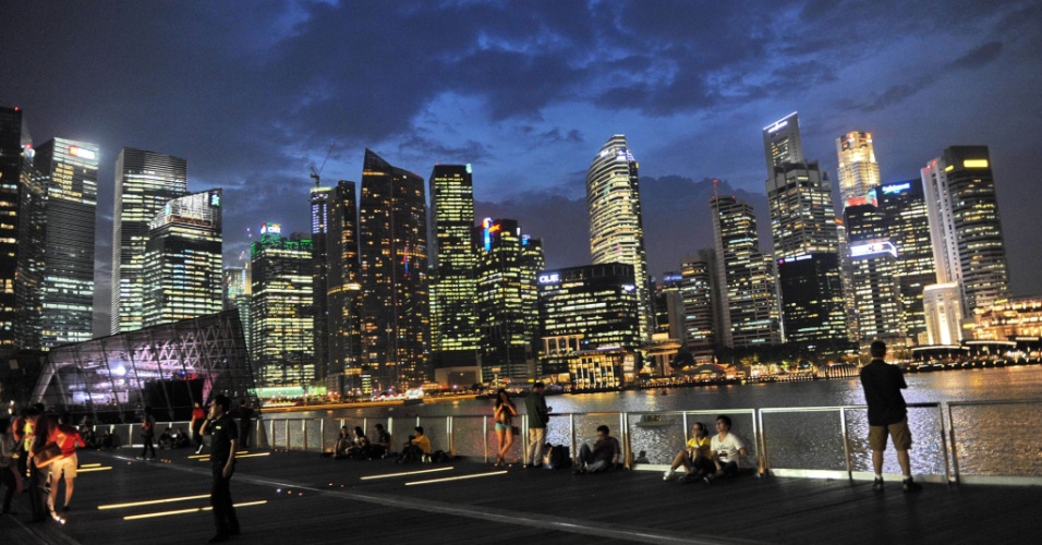 01.nov.2012 - Pessoas se sentam ao longo do passeio da Marina Bay, com vista para o distrito financeiro de Cingapura