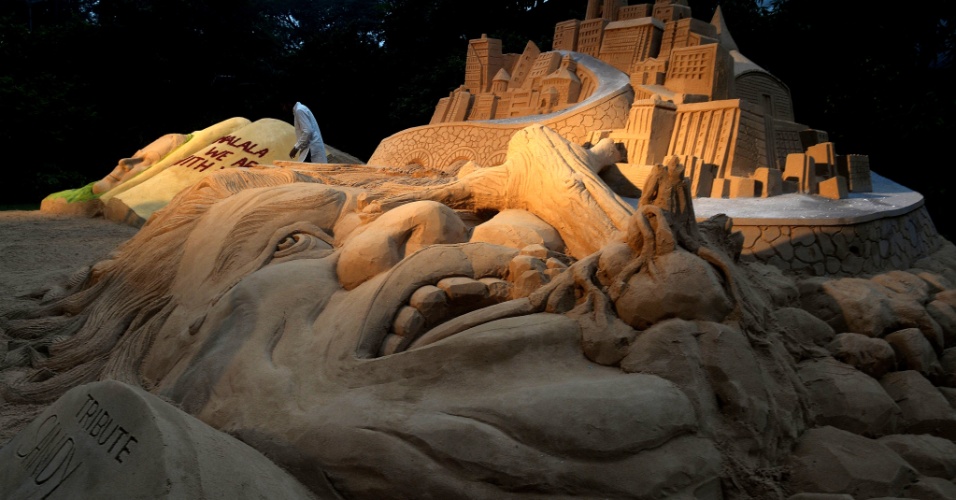3.nov.2012 - Escultor indiano Sudarshan Pattanayak (de branco, ao fundo) dá os últimos retoques em uma escultura de areia em homenagem às vítimas do furacão Sandy durante oficina deste tipo de arte realizado em Calcutá, Índia