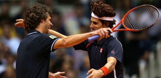 Gustavo Kuerten ri e abraça Novak Djokovic, na imitação de Guga feita pelo sérvio - EFE/Marcelo Sayão