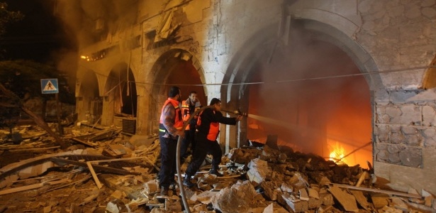 Bombeiros tentam apagar fogo no prédio do Banco Nacional Islâmico, em Gaza, causado por ataque israelense - Majdi Fathi/AFP