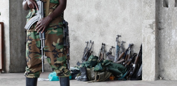 Integrante do grupo rebelde M23 monta guarda em frente às armas entregues por soldados do governo que se renderam na cidade de Goma (República Democrática do Congo), após ataque rebelde em novembro de 2012 - James Akena/Reuters