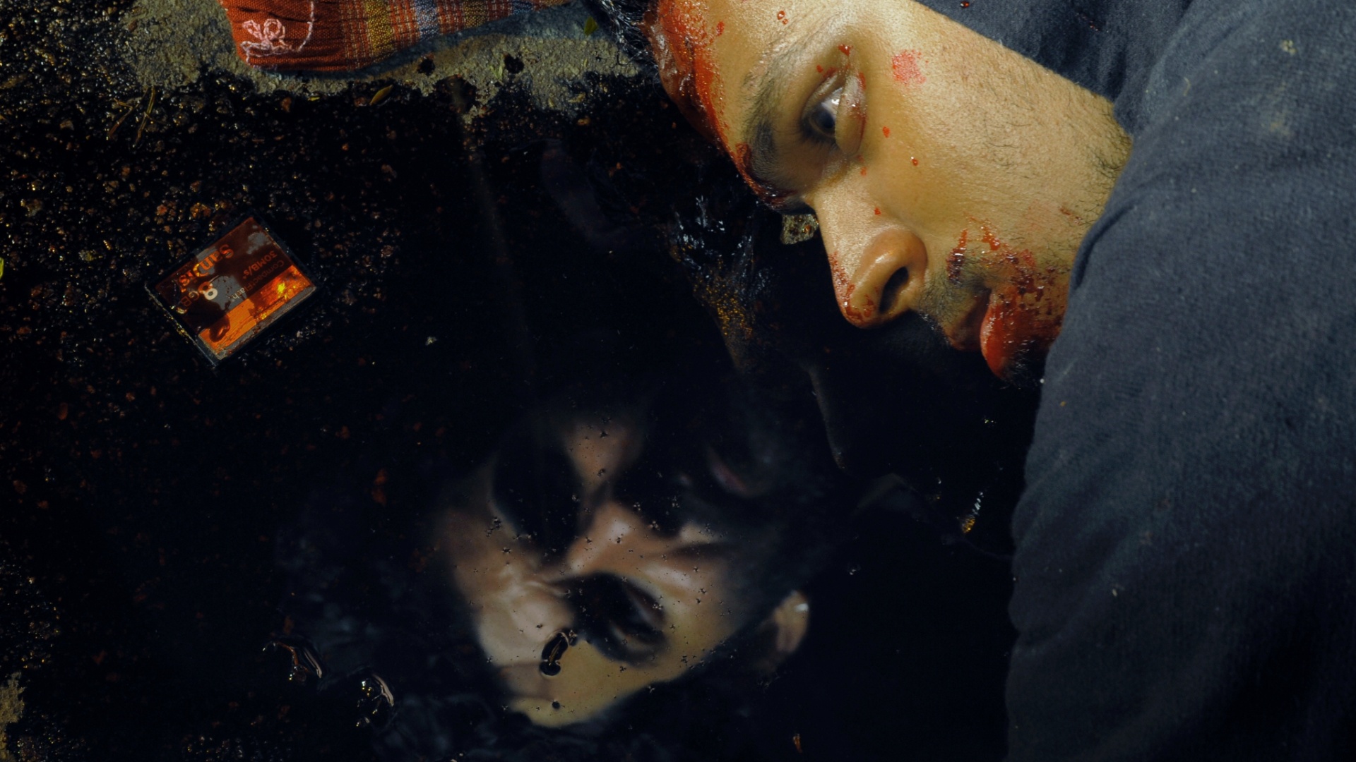 Cena do filme "Disparos", de Juliana Reis e estrelado por Gustavo Machado (rosto refletido na poça de sangue) e Caco Ciocler - Divulgação