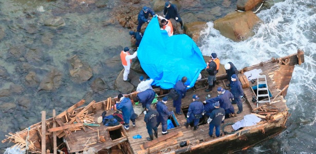 Policiais examinam barco de madeira onde foram encontrados cinco corpos, nesta quarta-feira (28) - Kyodo/Reuters