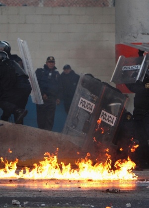Policiais se protegem de bombas de coquetel molotov lançadas por mexicanos que são contra o novo presidente do país