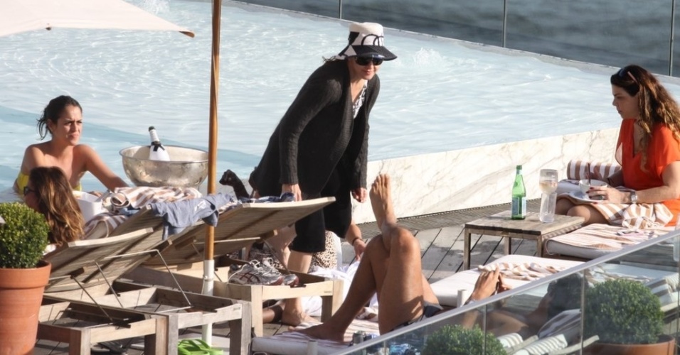 1.dez.2012: De chapéu e manga comprida, Madonna se protege debaixo do guarda-sol em piscina do hotel. A cantora apresenta domingo (2) no Rio de Janeiro