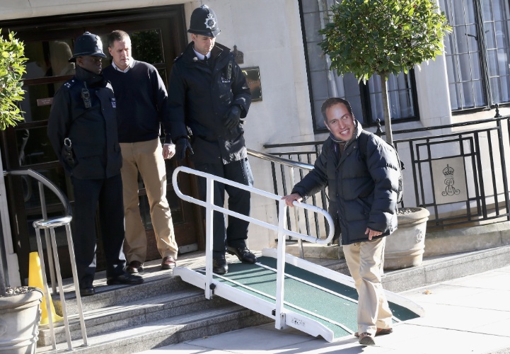 4.nov.2012 - Usando uma máscara com o rosto do príncipe William, homem é levado para longe da entrada do hospital particular King Edward Vll, em Londres