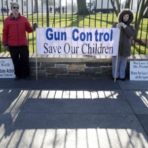 15.dez.2012 - 15.dez.2012 - Manifestantes seguram cartaz que diz ''Controle de armas salva as nossas crianças'' em frente à Casa Branca, em Washington (EUA), neste sábado