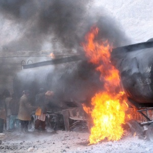 Afegãos coletam gasolina de um tanque de óleo em chamas, depois que militantes do Taleban atacaram um veículo que transportava suprimentos para soldados da Otan, em Doshi, no Afeganistão - Jawed Kargar/Epa/Efe 