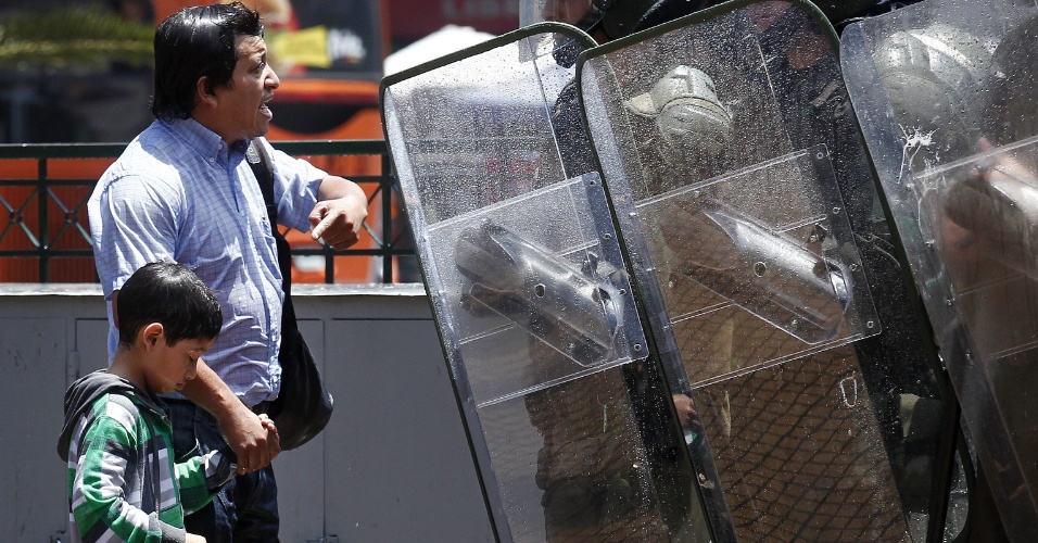 21.dez.2012 - Pai reclama com policiais após seu filho ser atingido por um jato d'água durante protesto de estudantes no Chile; movimento pede reforma educacional no país desde 2011