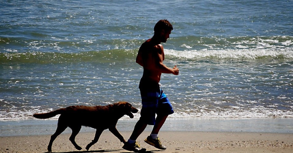 24.dez.2012 - Banhista passeia com cachorro na Praia de Garopaba, no litoral catarinense, nesta segunda-feira (24)