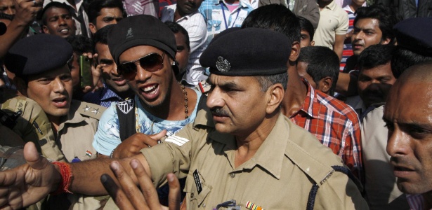 Ronaldinho é escoltado por policiais ao chegar em Pune, na Índia, onde irá promover o filme "R10" - AFP 