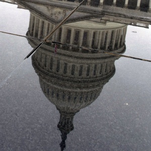 O Capitólio, sede do Poder Legislativo dos EUA, é refletido em poça de água na calçada, em Washington - Karen BLEIER/AFP
