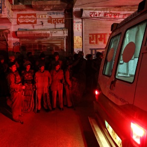 Policiais e curiosos se reúnem fora da casa da universitária que foi violentada e morta, em Nova Déli, Índia