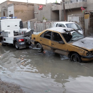 Caminhão da polícia guincha carro danificado após explosão no distrito de Karada, em Bagdá