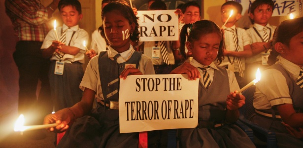 Crianças seguram cartazes enquanto rezam durante vigília por estudante vítima de estupro coletivo