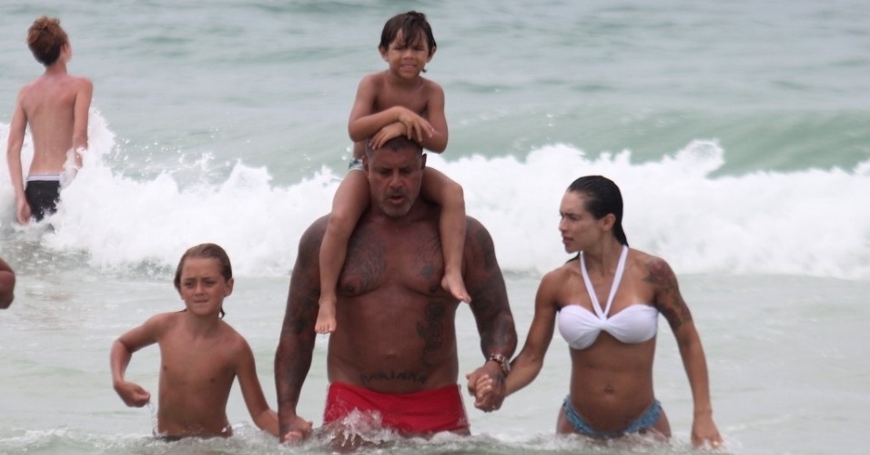 2.jan.2013 De sunga vermelha, Alexandre Frota curte praia na Barra da Tijuca ao lado do enteado Enzo e da mulher Fabiana Frota