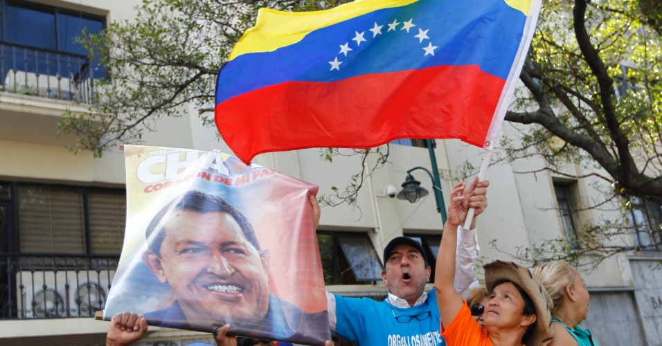 5.jan.2013 - Homem segura bandeira da Venezuela ao lado de cartaz de apoio ao presidente Hugo Chávez, que está hospitalizado em estado grave em Cuba