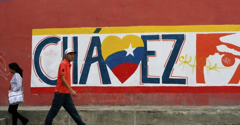 8.jan.2013 - Homem passa por muro com pichação com frase e cartazes de apoio ao presidente venezuelano Hugo Chávez, nesta quarta-feira (9). Segundo a Constituição da Venezuela, Chávez precisa ser empossado para o quarto mandato na quinta-feira (10), mas o governo defende o adiamento da posse por causa do estado de saúde do presidente venezuelano