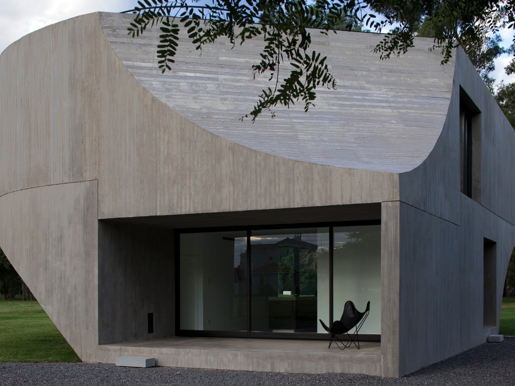 Os recortes elípticos, retangulares e esféricos em concreto remetem ao modernismo brasileiro dos anos 1940, 50 e 60, se aproximando das técnicas aplicadas por arquitetos como Oscar Niemeyer. Ao longo de todo o perímetro da casa são encontrados vãos diferenciados no formato, em seu tamanho ou recuo em relação à fachada. Tais características são dadas em função do uso dos interiores, sua orientação em relação ao sol ou ao horizonte. O projeto é de Diego Arraigada, Mark Lee e Sharon Johnston - Leonardo Finotti/ UOL