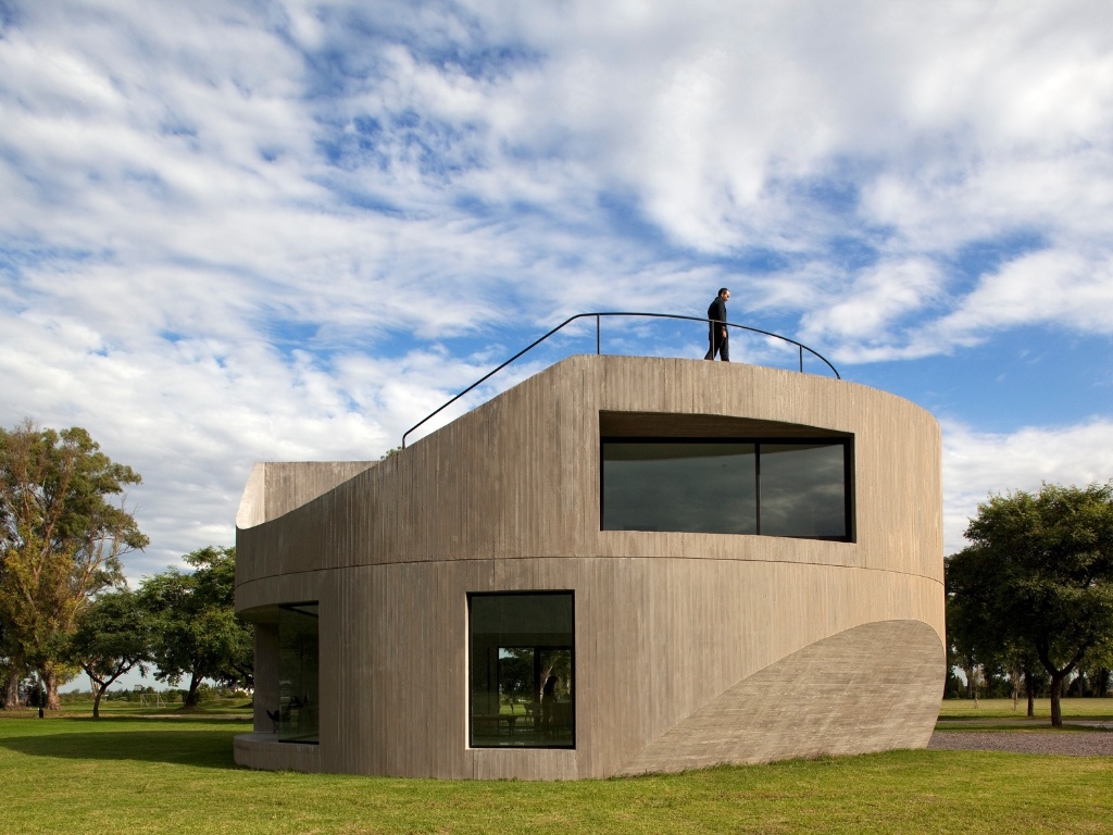 Para o norte, a fachada assume uma dinâmica rotacional pura: esta é a principal face da edificação a receber luz solar, assim a inserção da janela superior no monolito de concreto, em ângulo, garante que o interior do pavimento receba maior quantidade de luz pela manhã, quando o sol é mais ameno. A View House, na Argentina, foi projetada por Diego Arraigada, Mark Lee e Sharon Johnston - Leonardo Finotti/ UOL