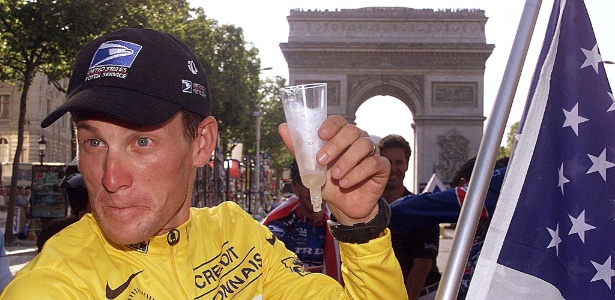 Norte-americano Lance Armstrong brinda com champanhe em frente ao Arco do Triunfo, em Paris, após conquistar pela primeira vez o título da Volta da França - AFP PHOTO / JOEL SAGET