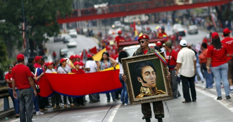 23.jan.2013 - Apoiadora do presidente venezuelano, Hugo Chávez, segura quadro com imagem do revolucionário latino-americano, Símon Bolivar, durante uma marcha em Caracas, na Venezuela, para celebrar 55 anos de democracia no país, com a queda da ditadura de Marcos Pérez Jiménez (1952-1958). Os manifestantes também homenageam, Chávez, líder da Revolução Bolivariana, que se recupera de uma operação contra um câncer realizada em Cuba há um mês e meio