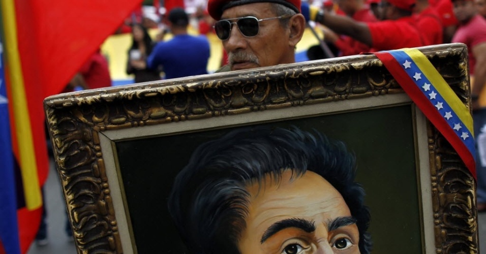 23.jan.2013 - Apoiador do presidente venezuelano, Hugo Chávez, segura quadro com imagem do revolucionário latino-americano, Símon Bolivar, durante uma marcha em Caracas, na Venezuela, para celebrar 55 anos de democracia no país, com a queda da ditadura de Marcos Pérez Jiménez (1952-1958). Os manifestantes também homenageam, Chávez, líder da Revolução Bolivariana, que se recupera de uma operação contra um câncer realizada em Cuba há um mês e meio