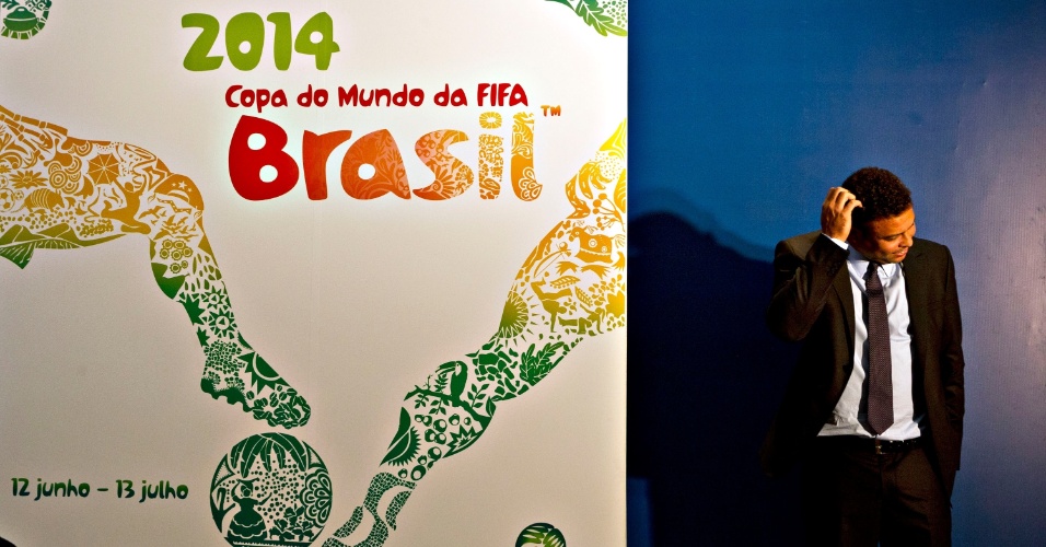 30.jan.2013 - Ronaldo coça a cabeça ao lado do recém-revelado cartaz da Copa do Mundo de 2014