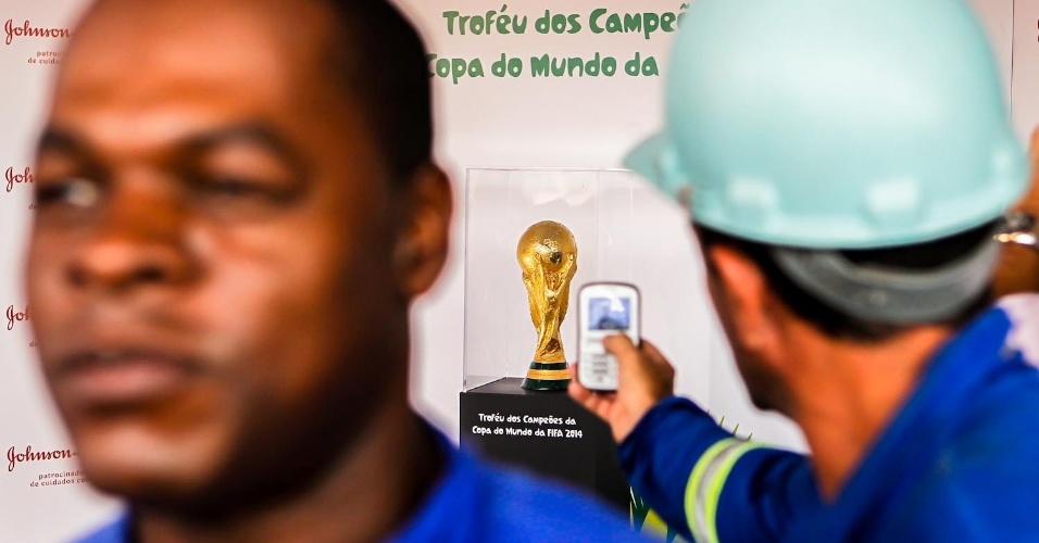 05.fev.2013 - Operários do Itaquerão tiram foto da taça da Copa do Mundo exposta no estádio