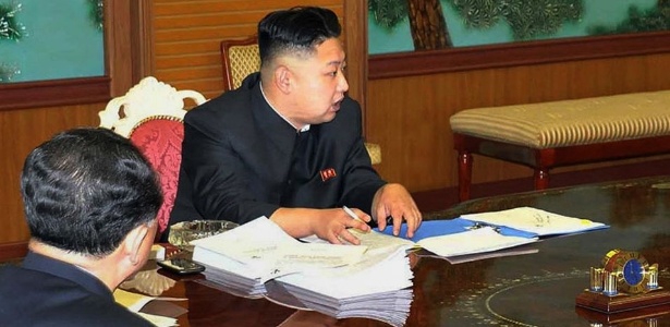 Líder norte-coreano, Kim Jong-Un, aparece ao lado de um smartphone preto durante reunião de governo - KNS/AFP